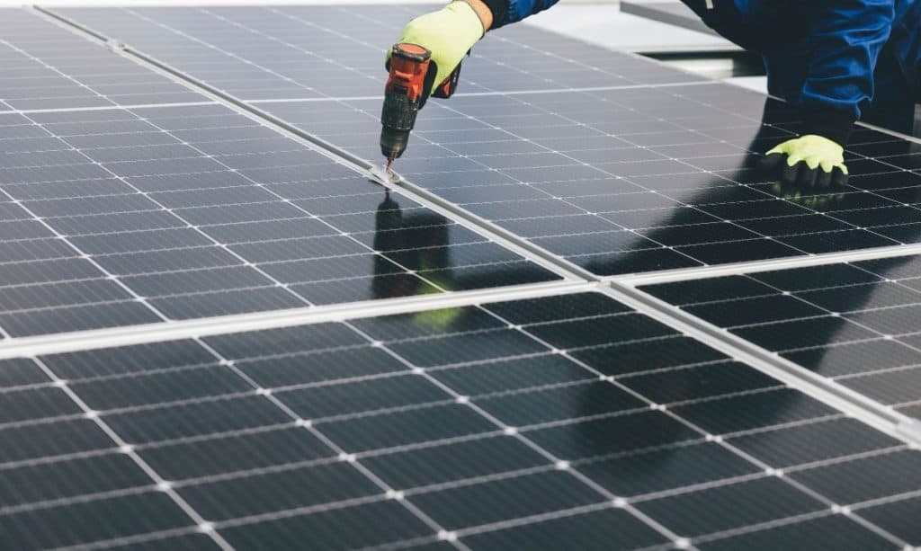 Aurinkopaneelijärjestelmän asennus. Ammattilainen asentaa aurinkopaneelit omakotitalon katolle